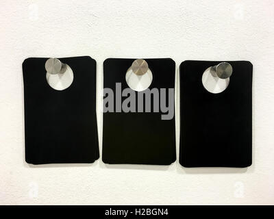 Three Blank Black Tags On White Wall Stock Photo
