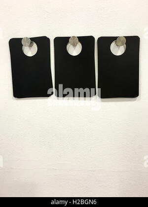 Three Blank Black Tags On White Wall Stock Photo