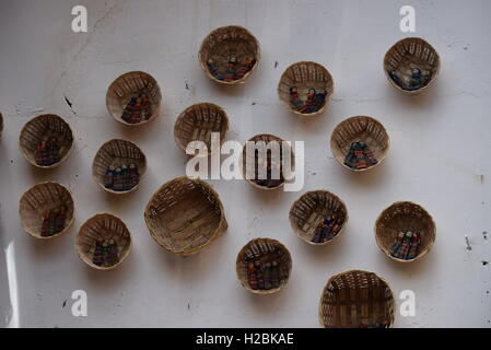 Worry dolls in wicker baskets hanging on the wall of a restaurant in Antigua, Guatemala Stock Photo