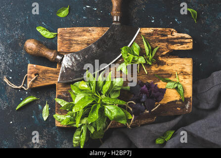 Fresh basil and vintage herb chopper on rustic wooden board Stock Photo