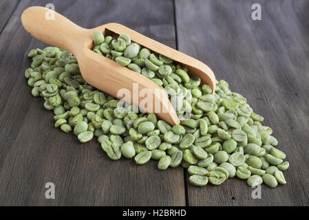 Green coffee beans in wooden scoop on vintage wooden surface Stock Photo