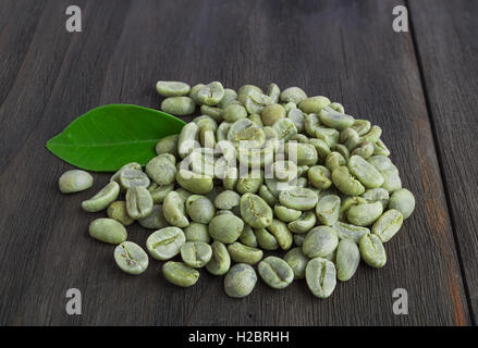 Green coffee beans with leaf  on vintage dark wooden surface Stock Photo