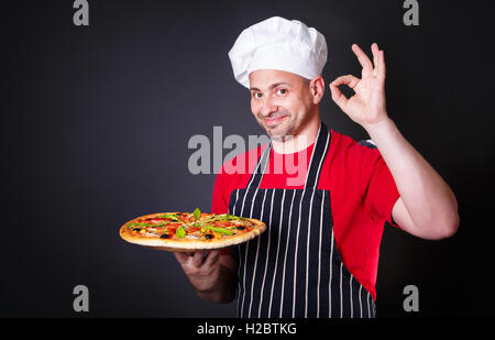 Portrait of happy attractive cook with a pizza in his hands Stock Photo