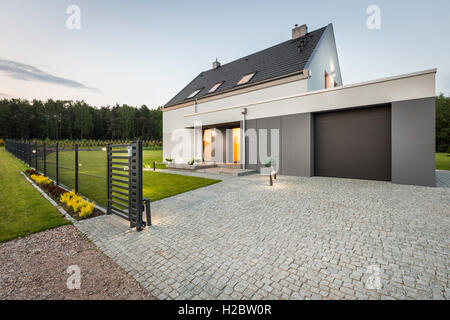 Stylish villa with fence, garage and stone driveway, external view Stock Photo