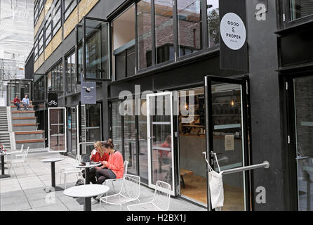 Young women with laptop computers drinking tea outside "Good & Proper Tea" shop at The Bower, Old Street, Tech City, London EC1V UK  KATHY DEWITT Stock Photo