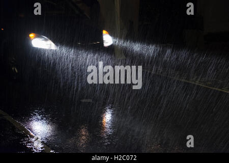 A cars headlights shine through heavy rain at night Stock Photo