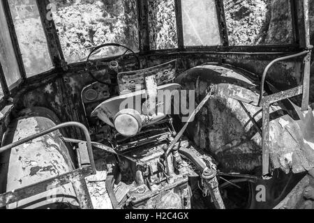 Old abandoned rusted tractor cabin interior, black and white retro style photo Stock Photo