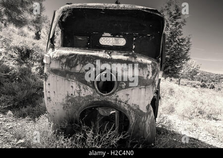 Abandoned rusted body of three-wheeled light commercial vehicle, old style filter effect, monochrome retro photo Stock Photo