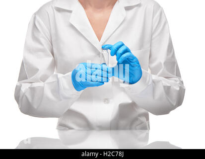 Close up of female doctor in white medical gown and blue sterilized surgical gloves holding empty white glass ampoule Stock Photo