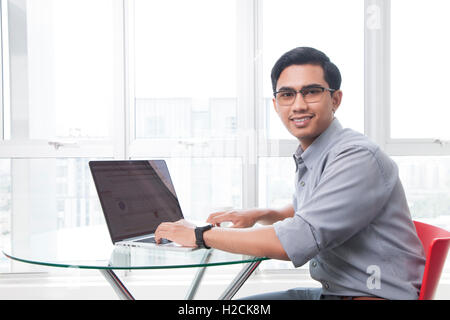 Smiling businessman using laptop in office Stock Photo