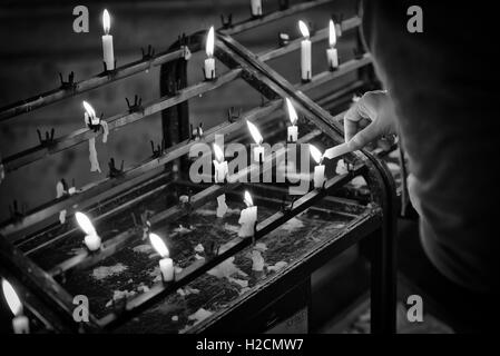 Woman lighting a candle to say a prayer at St. Paul's Cathedral in London. Stock Photo