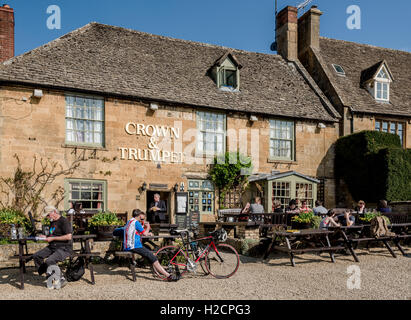 People enjoying an early evening drink in the sunshine in front of a typical village pub in the Cotswolds. Stock Photo