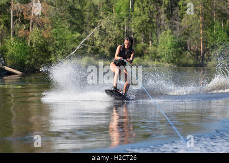 Young pretty woman study riding wakeboard on a lake Stock Photo