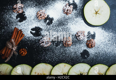 Halloween background with flying bats. Sliced apple, cinnamon sticks and walnuts over dark background. Top view Stock Photo