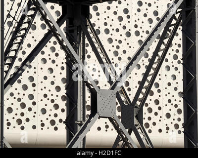 abstract design formed from angular ladder and steelwork in bright sunshine with background of concrete with bubble-like holes Stock Photo