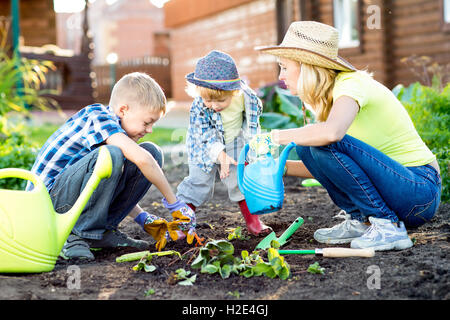 two children brothers as gardeners with their mother - kids and family Stock Photo