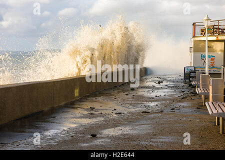 Waves crash over the sea wall at Westward Ho! during a spring tide scattering debris over the promenade. Stock Photo