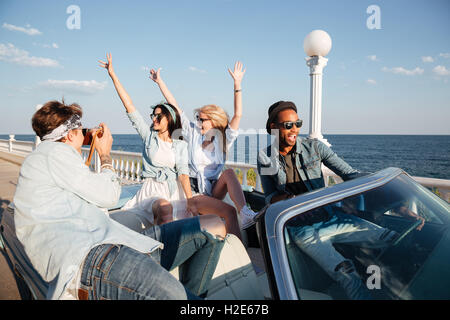 Group of happy young people taking photos and having fun in cabriolet Stock Photo