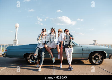 Multiethnic group of cheerful young people standing near vintage cbriolet Stock Photo