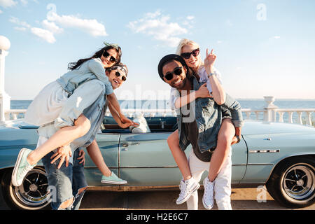 Two happy young men holding their girlfriends and smiling in summer Stock Photo