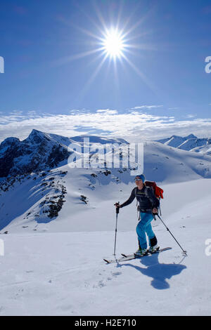 Ski tourer ascending Burstinden, snowy mountain landscape, Senja, Norway Stock Photo