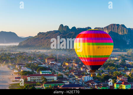 Colorful hot air balloon drifts over the city, karst mountains behind, Cityscape, Vang Vieng, Vientiane Province, Laos Stock Photo