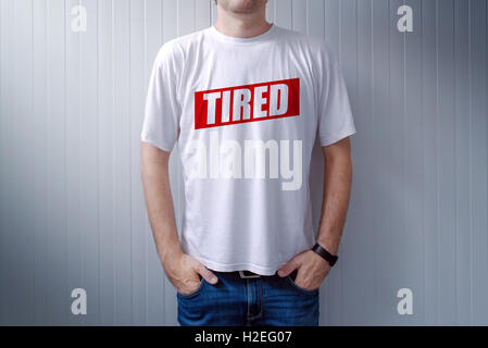 Guy wearing white t-shirt with label Tired printed on chest, text is added in post production Stock Photo