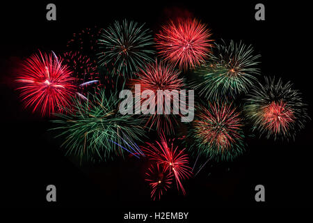 Colorful fireworks of various colors over night sky. Celebration beautiful colorful fireworks, red green salute with dazzling di Stock Photo