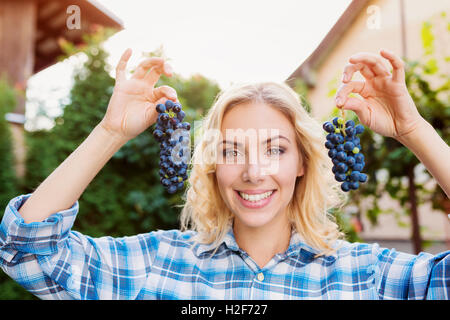 Woman in checked shirt holding two bunches of grapes Stock Photo