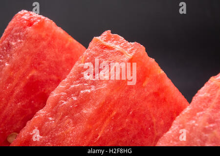 slices of ripe juicy watermelon in red plate on black background Stock Photo