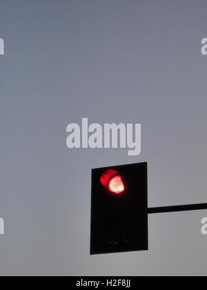 red traffic light at dusk against a clear blue sky, milan Stock Photo