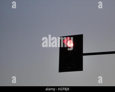 red traffic light at dusk against a clear blue sky, milan Stock Photo