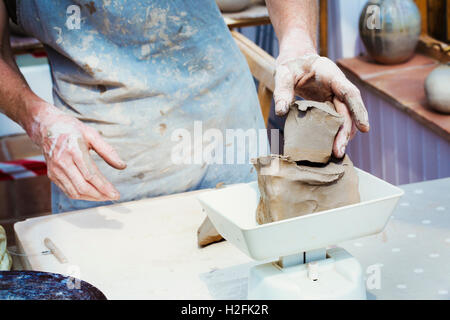 A woman potter working clay measuring it on  a weighing scale. Stock Photo