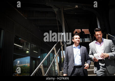 Two businessmen wearing grey suits walking down a staircase at the entrance of a building. Stock Photo