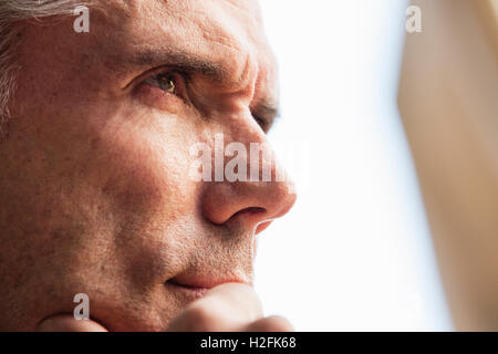 Close up of a man's face, his hand on  his chin, looking into the distance. Stock Photo
