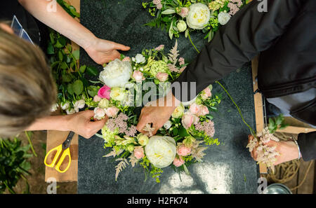 A florist's workshop. Overhead view of two women working on  an arrangement. Stock Photo