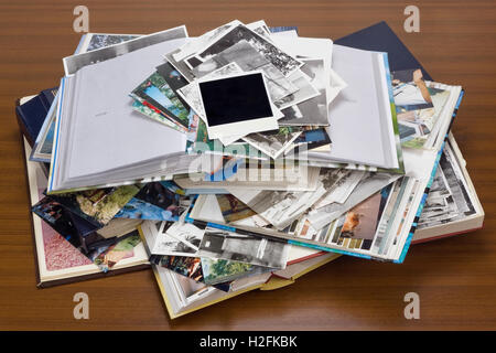 Nostalgia by youth - old family photo albums and photos lie a heap on a wooden table. Stock Photo