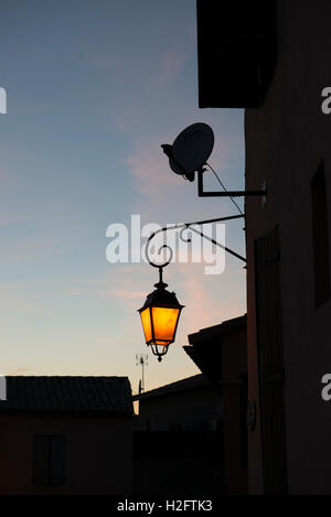 Shining street lantern at dusk, St. Gilles, Gard department, southern France Stock Photo
