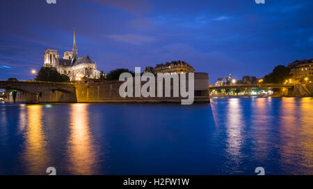 The iconic gothic Cathedral Notre Dame De Paris and the River Seine seen from the Quai de la Tournelle at night Stock Photo