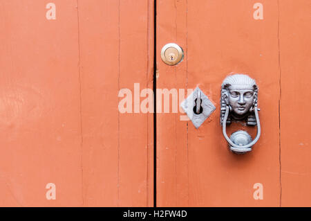 Head of the Sphinx with iron knocker on old wooden door. Lock and key. Alchemy, mystery. Orange Stock Photo