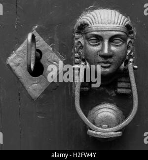 Head of the Sphinx with iron knocker on old wooden door. Lock and key. Alchemy, mystery. Black and White Stock Photo