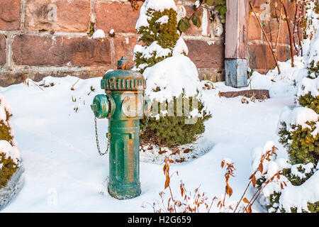 Green hydrant in the snowy rock garden Stock Photo