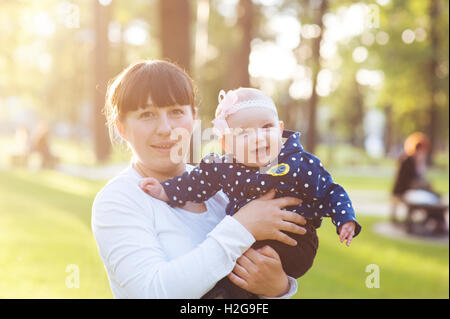 young mother carrying a baby girl and walks in the park Stock Photo