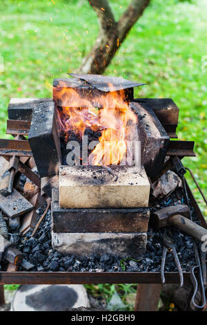 steel rod is heated in rural forging furnace in burning coals Stock Photo