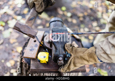 Blacksmith forges hot red iron rod in vise in outdoor rural smithy Stock Photo