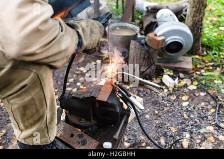Welder welds buckle by point electric welding in outdoor rural workshop Stock Photo