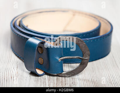 hand made blue leather belt with forged buckle on wooden table Stock Photo