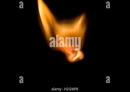 A match being lit isolated against a dark black background Stock Photo