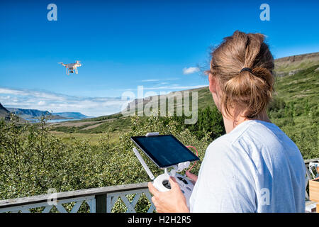 Young man flying a drone in a rural setting on bright summer day, holding the remote control and looking at the drone Stock Photo