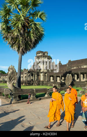 SIEM REAP, CAMBODIA - OCTOBER 30, 2014: Novice Buddhist monks in saffron orange robes pass in front of Angkor Wat. Stock Photo